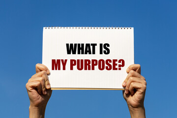 What is my purpose text on notebook paper held by 2 hands with isolated blue sky background. This...
