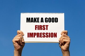 Make a good first impression text on notebook paper held by 2 hands with isolated blue sky background. This message can be used as business concept about making a good first impression.