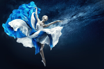 Ballerina dancing in Blue Chiffon Dress over Night Sky Background. Ballet Dancer jumping in...