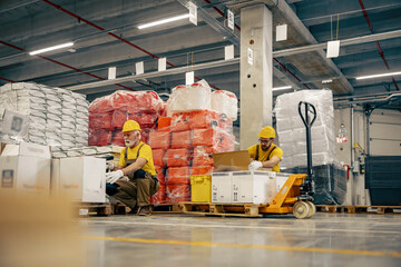 Fototapeta Warehouse workers  scanning barcodes on boxes in a large warehouse obraz
