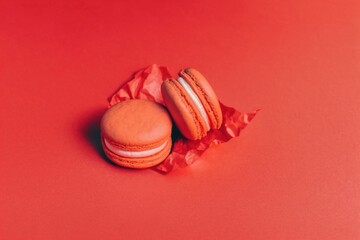 traditional french dessert, two red macarons stacked and isolated on a red surface and a red background