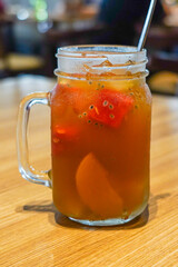 iced fruit tea, with pieces of fruit in a glass cup