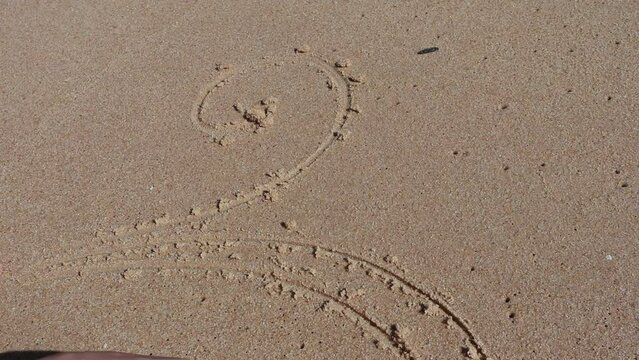 Girl drawing on  wet sand
