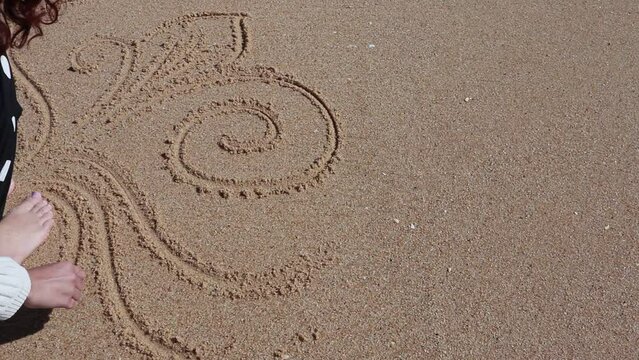 Girl drawing on  wet sand