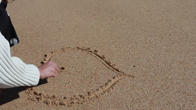 Girl drawing on  wet sand