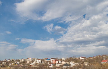 Fototapeta na wymiar Panorama of houses on a hill against a blue sky with clouds
