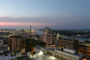 Fototapeta na wymiar Aerial shot of the Savannah River and the Talmadge Memorial Bridge with hotels, restaurants and office buildings in the city skyline at sunset in Savannah Georgia USA