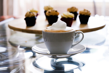 White cup of latte with mini chocolate cupcakes with peanut butter cream icing