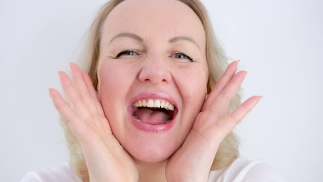 different cheerful positive emotions of a girl woman put 2 hands to her face opened her mouth laughing eyes smiling beautiful straight teeth on a white background middle age
