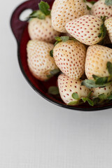 White Strawberries (Berry de Blanc) in a red bowl on white background