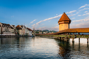 Horizontal photograph of Kapellbrücke in lucerne on a sunny day with few clouds in the background and some buildings, an image of Kapellbrücke in the city of Lucerne in Switzerland.