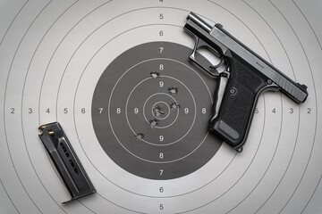 Shooting from a weapon.  9mm compact pistol and target for shooting with bullet holes in the center.