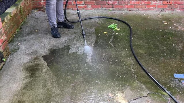 4K HD video of person power washing concrete and asphalt patio. Green algae and mold removed with garden hose power wash. 4x normal speed.
