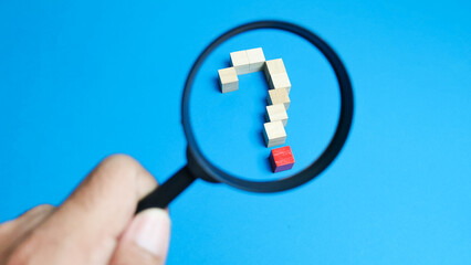 Wooden cubes arrange as question mark symbol with magnifying glass. Question mark concept.