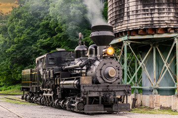 An Antique Shay Steam Locomotive, Steamed up, Blowing Smoke, Sitting by a Water Tower, Getting Ready for Work