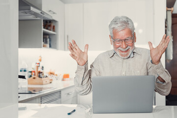 Happy excited old elderly man winner excited by reading good news looking at laptop, overjoyed...