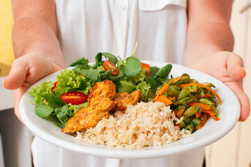 Healthy Meal with Grilled Chicken, Rice, Salad, and Vegetables Served by Woman