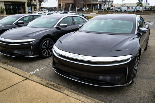 Photo of the front of two parked black Grand Touring Lucid Air luxury sedan electric vehicles. The cars get approximately 500 miles of range.