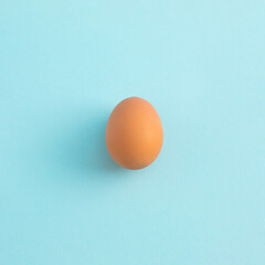 Uncooked egg on pastel blue background. Minimal food concept with copy space. Top view, flat lay.
