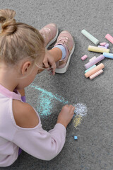 Naklejka premium Little child drawing flower with chalk on asphalt, closeup