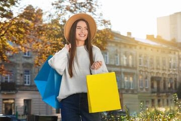 Beautiful young woman with shopping bags on city street