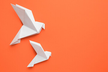 Beautiful white origami birds on orange background, flat lay. Space for text