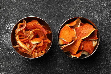 Bowls with dry orange peels on gray textured table, flat lay