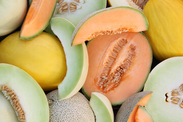 Different types of tasty ripe melons as background, top view
