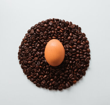 Uncooked egg and coffee roasted beans on white background. Flat lay, top view. Minimal Easter holiday composition. Food and drink concept.