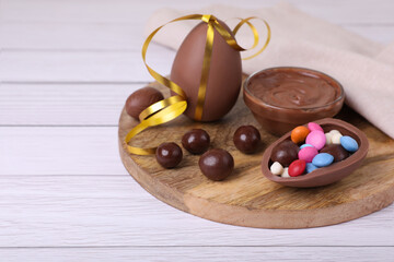 Fototapeta na wymiar Composition with delicious chocolate eggs and candies on white wooden table. Space for text