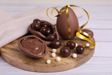 Composition with delicious chocolate eggs and candies on white wooden table, closeup