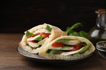 Delicious pita sandwiches with mozzarella, tomatoes and basil on wooden table