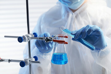 Scientist working with beaker and test tube in laboratory, closeup