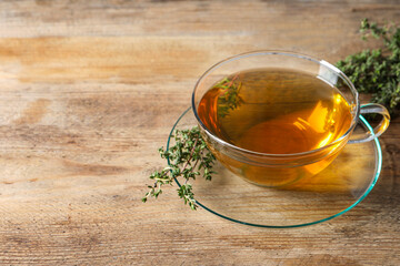 Aromatic herbal tea with thyme on wooden table, space for text