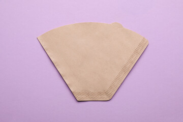 Paper coffee filter on lilac background, top view