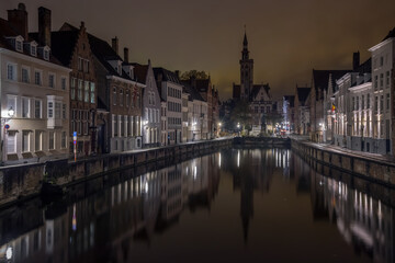 Cityscape with old buildings, canal and embankment in the evening city of Bruges (Belgium)