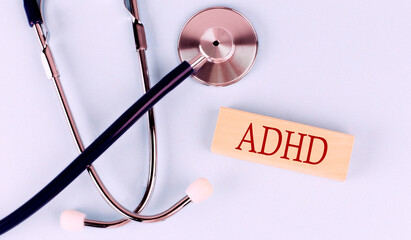 On a blue background, a stethoscope and wooden block with the word ADHD .Medical concept