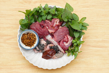 Fresh raw beef and Thai local herbal vegetables, prepare for cooking. Concept, food ingredient. Tradiotnal weird food. Popular menu in northern of Thailand.  Local food. Food ingredients to cook Larb.