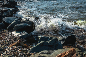 Large waves that occur during stormy weather break on the rocks of the breakwater. Coastal waves. White foam of the coastal wave on the sandy shore. Close-up of a wave on the Black Sea coast. 