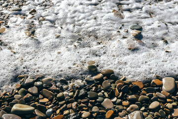 Close-up of a wave on the Black Sea coast. A soft sea wave on a sandy beach. White foam of the coastal wave on the sandy shore. Coastal waves. Selective focus. View of the waves of the Black Sea.