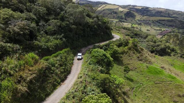 Autom&oacute;vil todoterreno viajando en carretera de terracer&iacute;a en monta&ntilde;as de Colombia, vista a&eacute;rea, dron