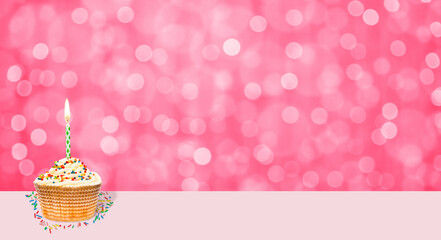 Birthday cupcake with burning candle against a blured background with copy space. Empty space for text. Shade trendy color of the year 2023 - Viva Magenta background
