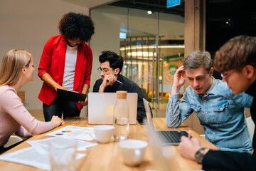 Group of young diverse businesspeople sitting together in boardroom. Group of successful business people attending morning briefing in modern meeting room. Multiethnic colleagues working together.