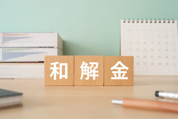 和解金と書かれたブロックが置かれたデスク