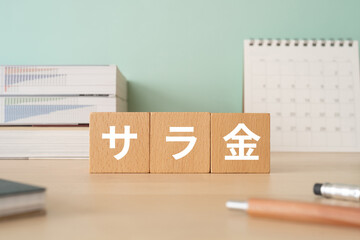 サラ金と書かれたブロックが置かれたデスク