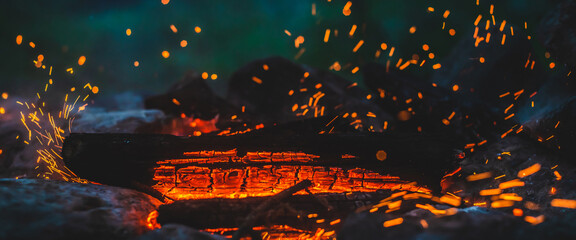 Vivid smoldered firewoods burned in fire close-up. Atmospheric background with orange flame of...