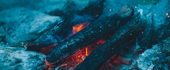 Vivid smoldered firewoods burned in fire close-up. Atmospheric warm background with orange flame of...