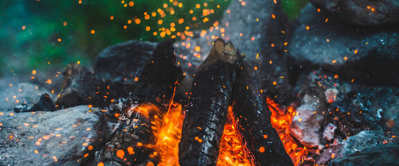 Vivid smoldered firewoods burned in fire closeup. Atmospheric background with orange flame of...