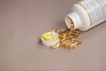 Capsules Omega 3 on beige background. Health care concept. White plastic medicine vial can jar with capsules.