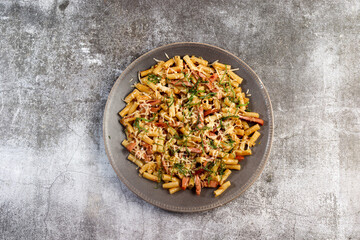 Homemade macaroni pasta with ham and cheese on a round plate on a dark background. Top view, flat lay